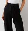 Close-up view of a model wearing the Maxine Black Wide Leg Trousers facing forward.